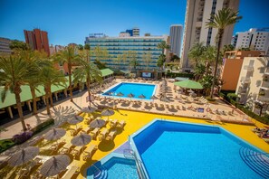 Ett poolområde vid hotellet med många solstolar, parasoller och en stor pool i mitten.