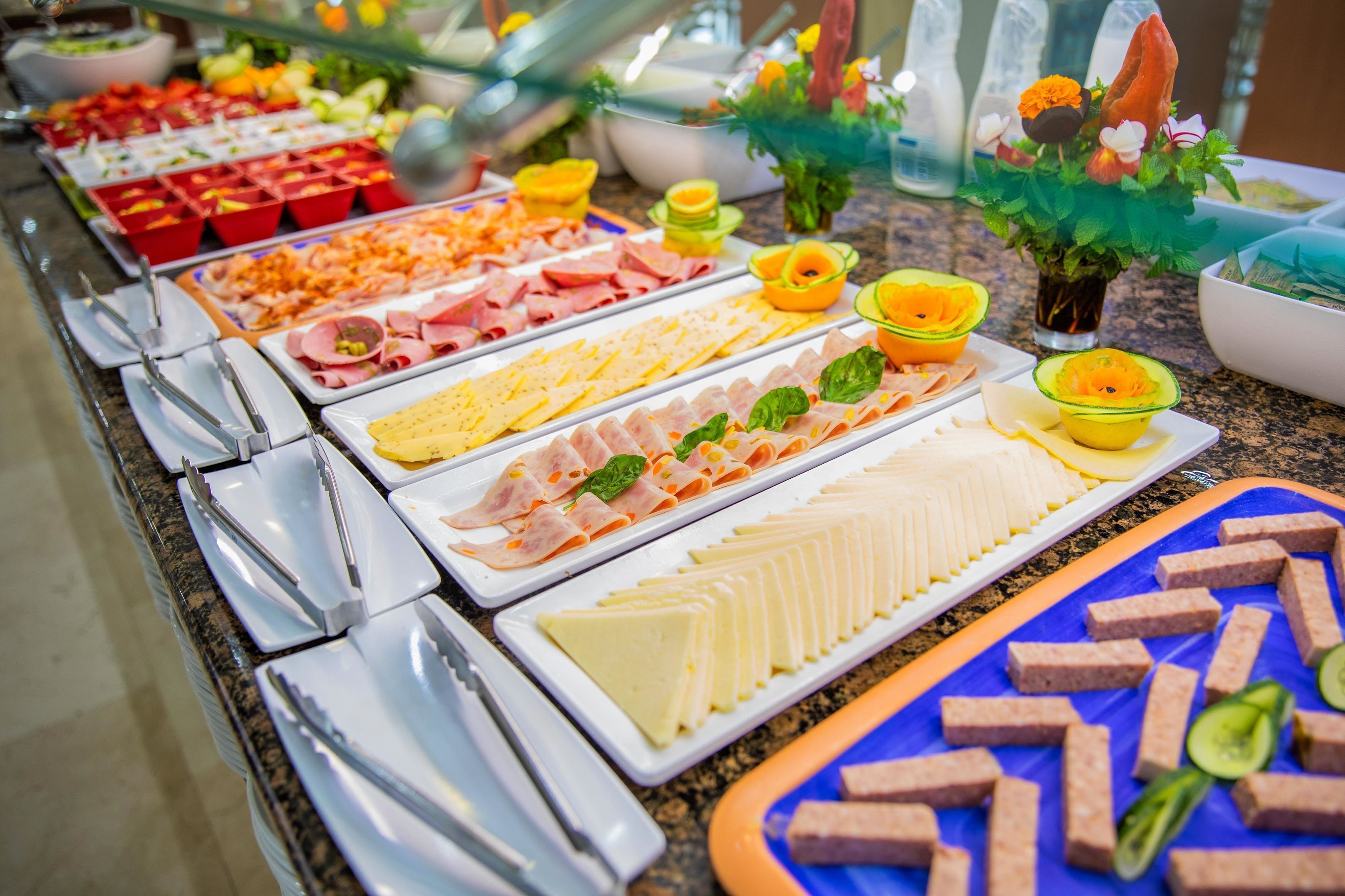 A buffet with various food items including meats, cheeses, and fruits.