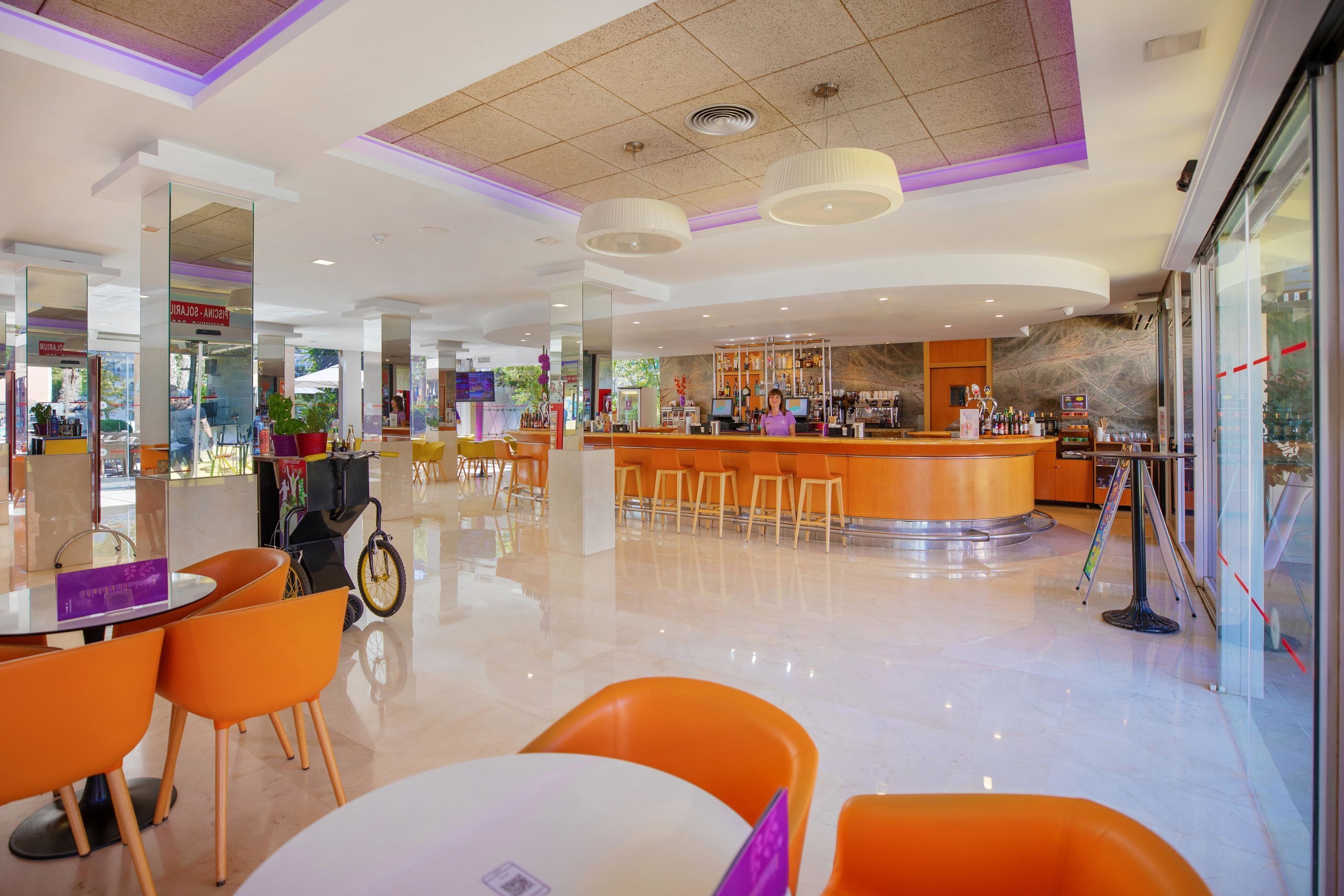 Un moderno vestíbulo de hotel con una zona de bar central, rincones de estar y un suelo limpio y pulido.