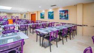 Un área de comedor con varias mesas y sillas, un atril y obras de arte en las paredes.