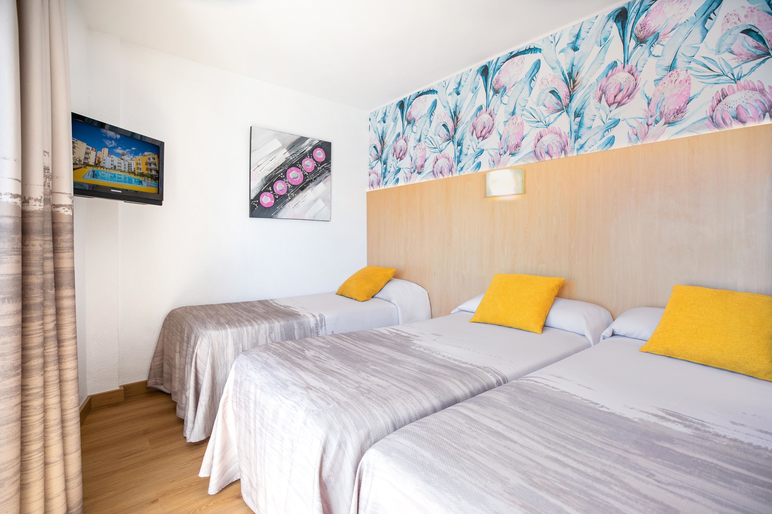 A hotel room with two beds, a wooden headboard, a painting, and a television.