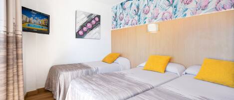 Ein Hotelzimmer mit zwei Betten, einem hölzernen Kopfteil, einem Gemälde und einem Fernseher.