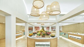 Een ruime, goed verlichte keuken met een centraal eiland, modern hangende verlichting en een verscheidenheid aan verse groenten en fruit, gepresenteerd op het eiland.