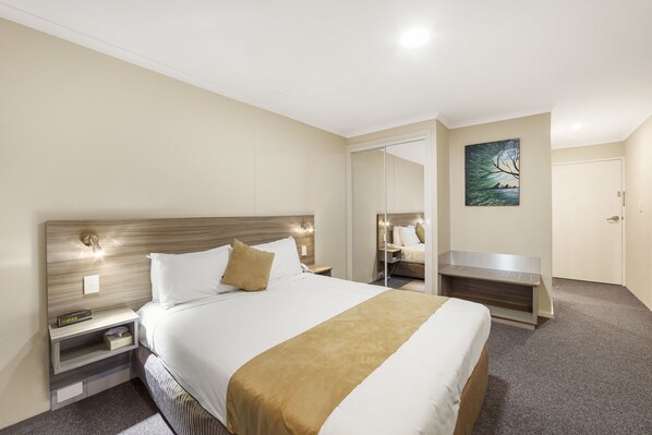 Habitación de hotel con una cama grande, mesitas de noche, un escritorio y un cuadro en la pared.