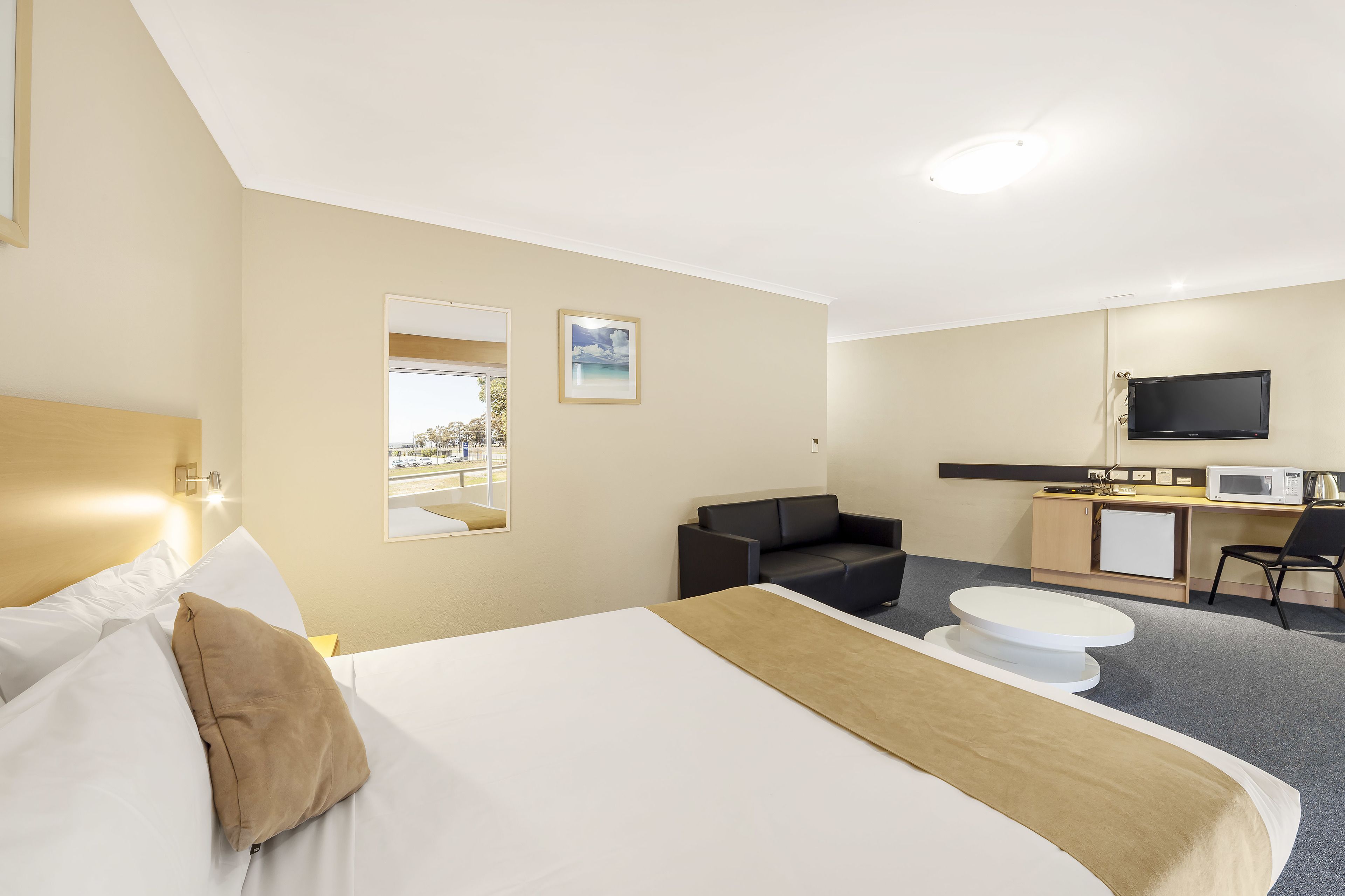 Une chambre d’hôtel équipée d’un lit, d’un bureau, d’une chaise, d’une télévision et d’un four à micro-ondes.