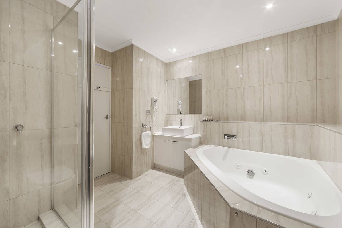 Ein modernes Badezimmer mit Duschkabine aus Glas, einer freistehenden Badewanne und einem Waschtisch mit Spüle und Spiegel.