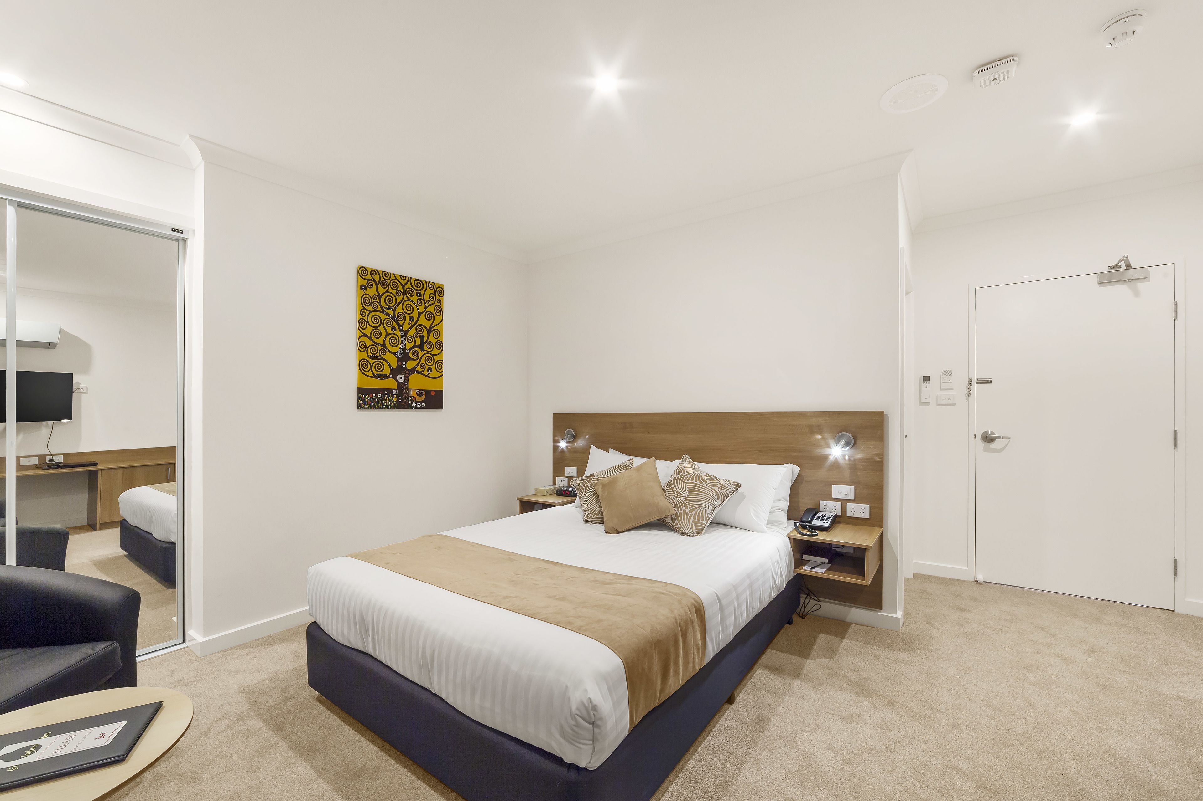A modern hotel room with a large bed, bedside tables, a desk, and a chair.