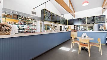 Una zona de bar con mostrador azul, sillas de madera y una pizarra de menú.