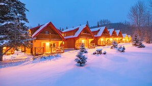 A row of log cabins with snow-covered roofs and a wooden deck in front. - Miette Mountain Cabins (Pocahontas)