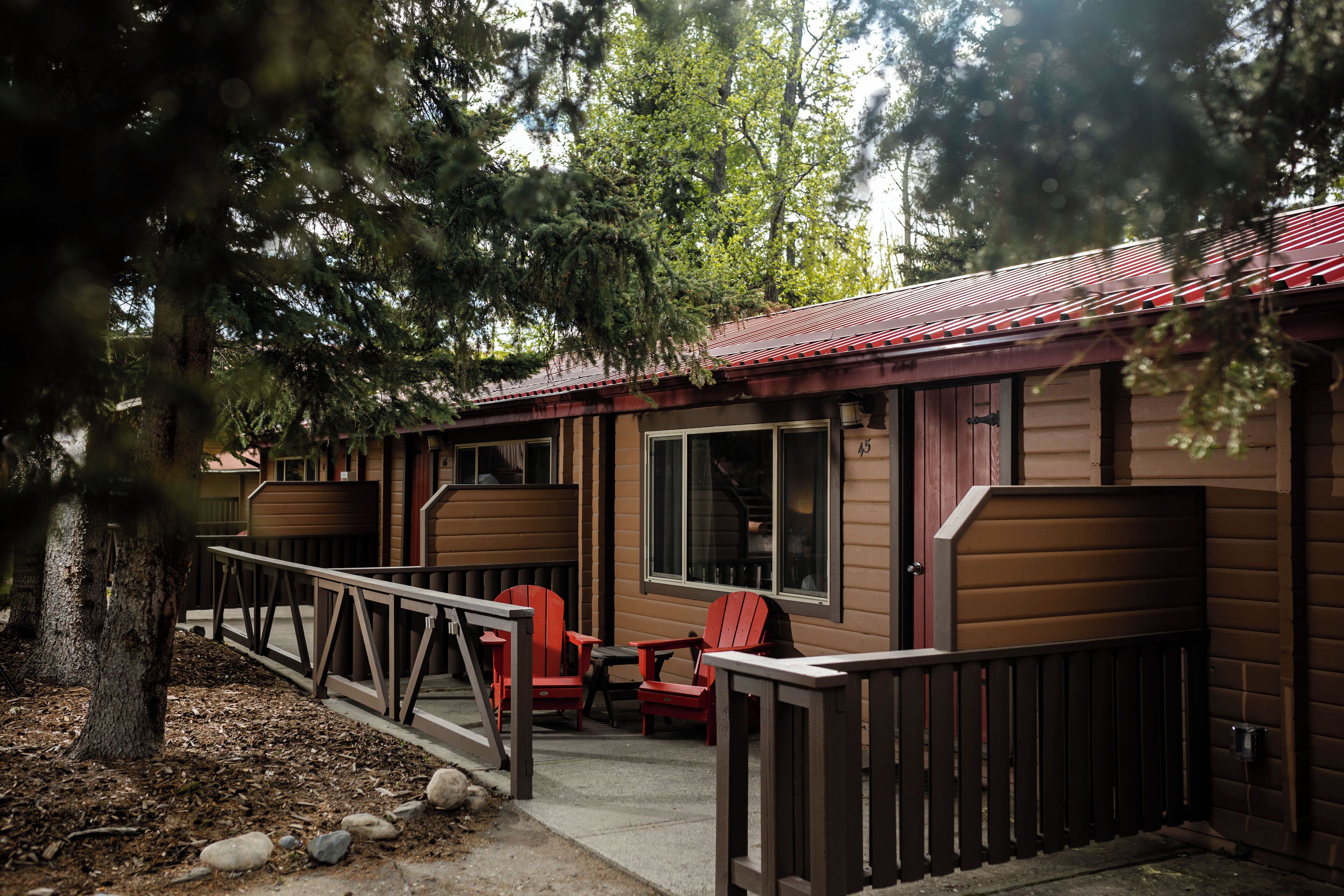 A cabin with a porch, red chairs, and a wooden deck.