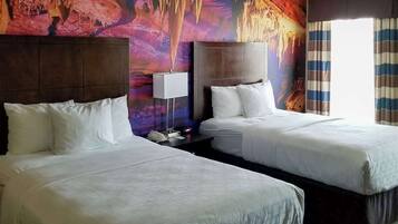 Une chambre d’hôtel avec deux lits, une grande fresque murale, une lampe de chevet et une fenêtre avec des rideaux.