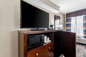 A hotel room with a flat-screen TV mounted on the wall, a microwave, and a coffee maker on a wooden cabinet. - Quality Inn Corydon (Corydon)