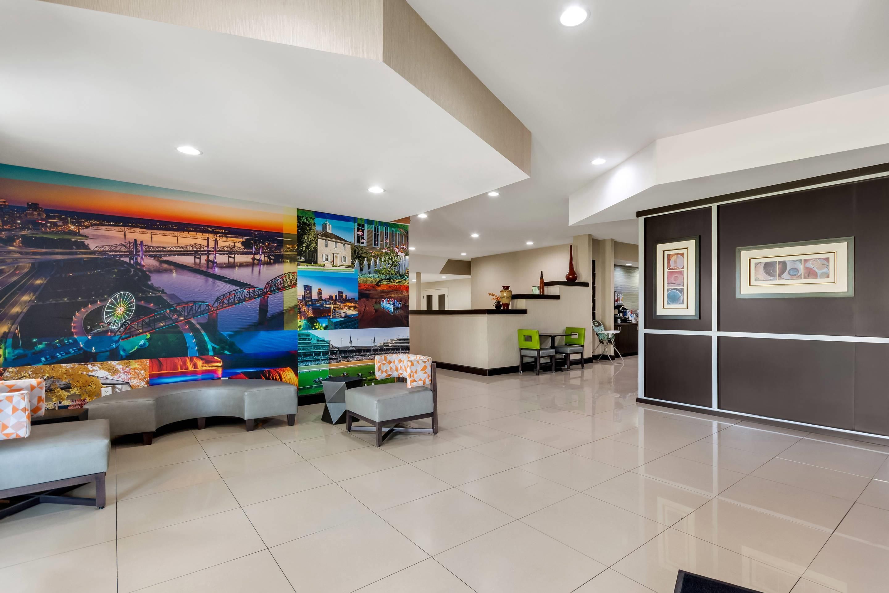 A hotel lobby with a large mural, seating area, and a reception desk.