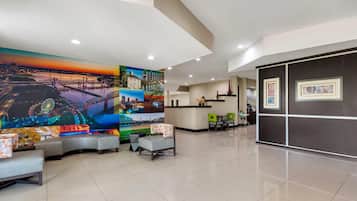 Un vestíbulo de hotel con un mural grande, una zona de estar y una recepción.