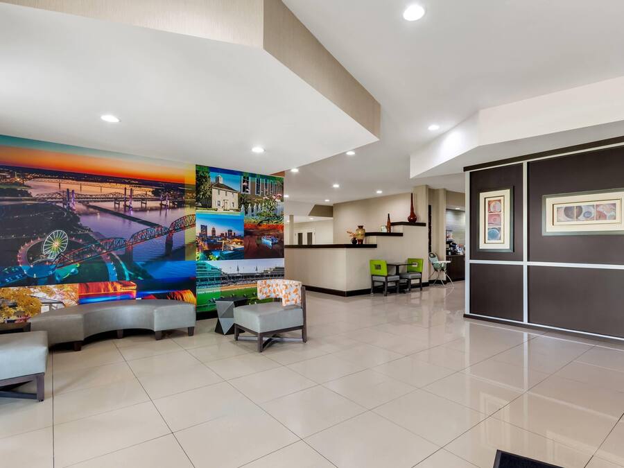 A hotel lobby with a large mural, seating area, and a reception desk.
