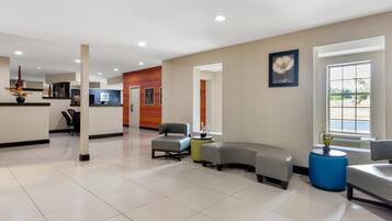 A spacious lobby with a reception desk, seating area, and a large window providing natural light.