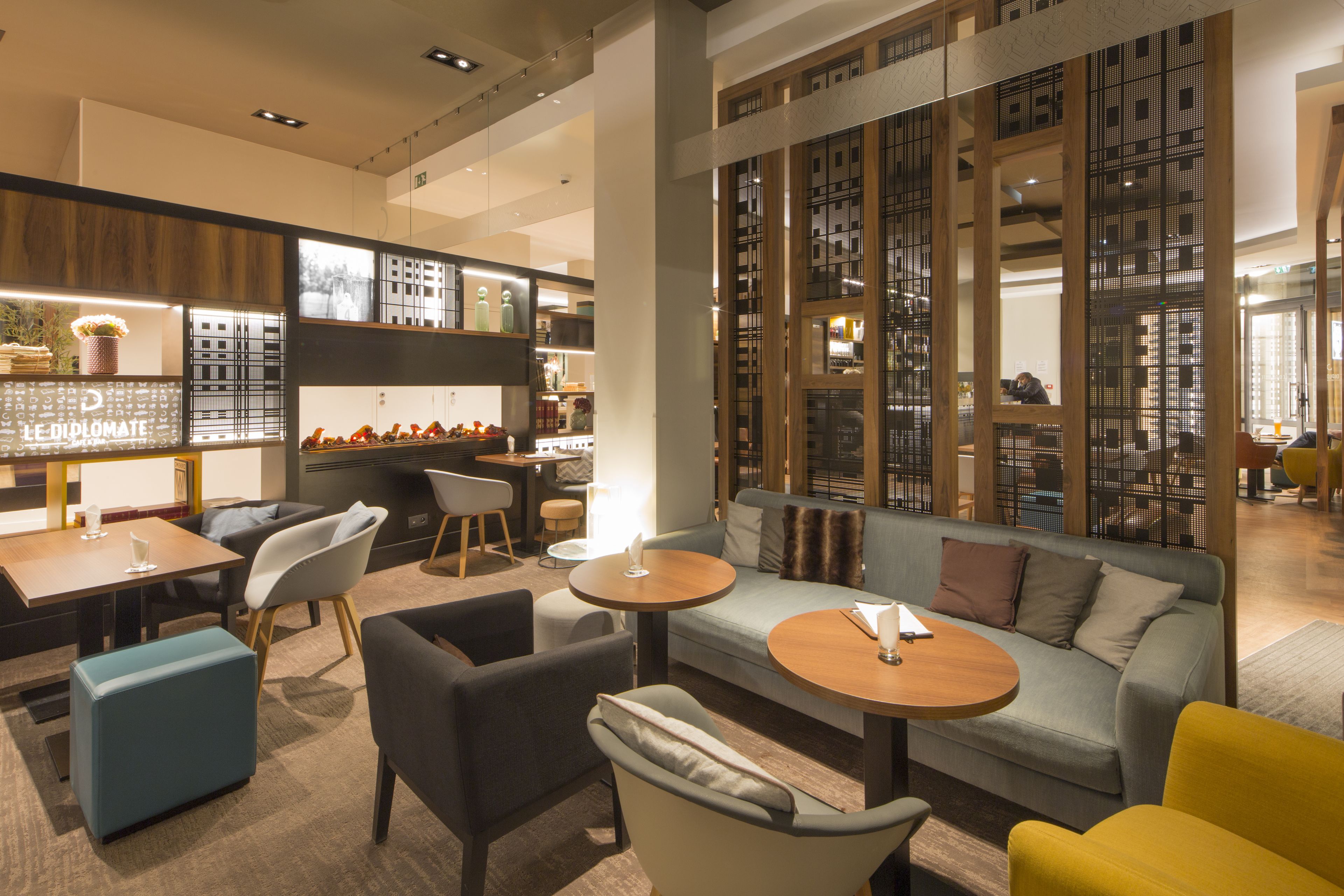 A modern hotel lobby with seating areas, a reception desk, and a decorative wall with a cityscape view.