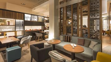 A modern hotel lobby with seating areas, a reception desk, and a decorative wall with a cityscape view.