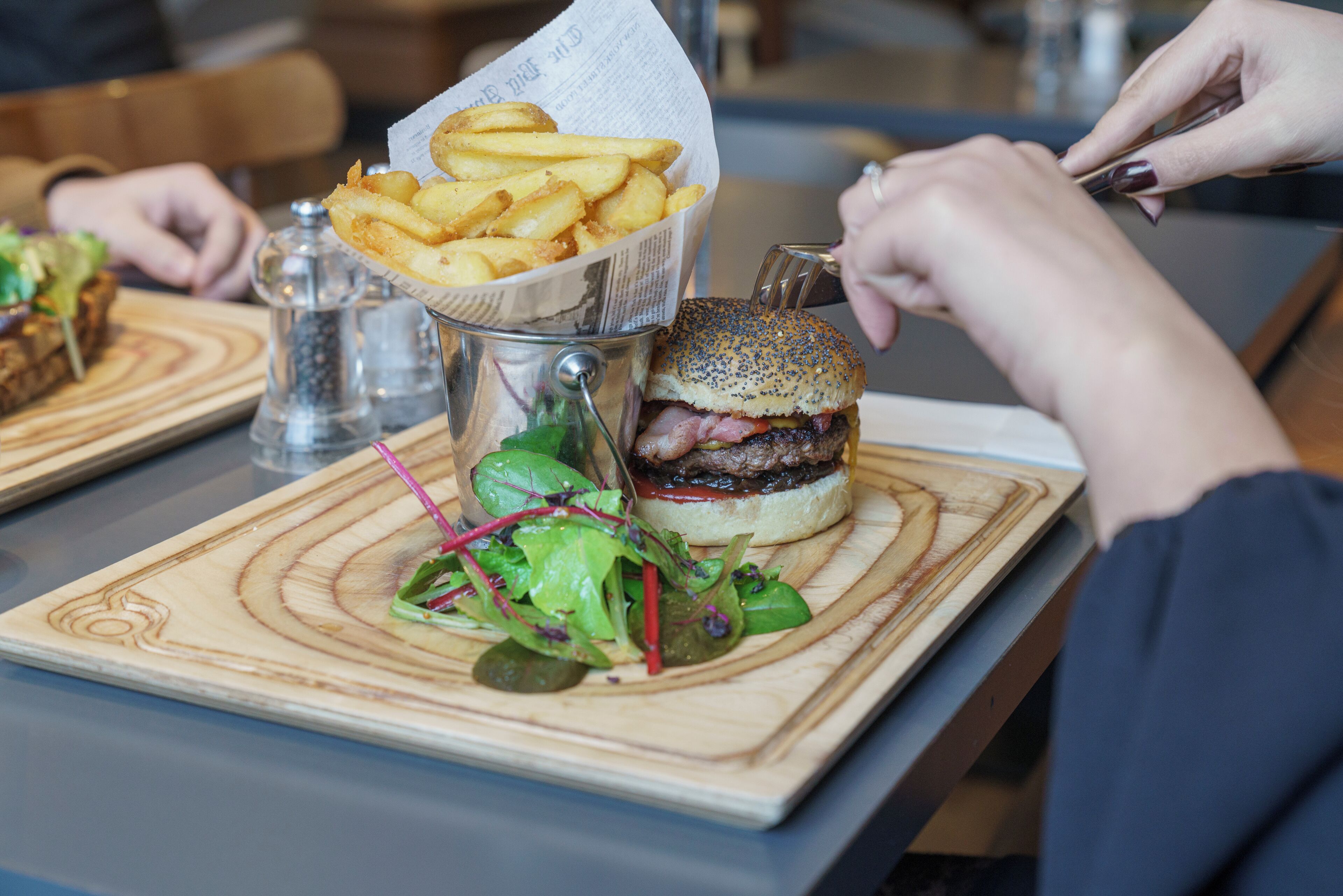 A meal with a burger, fries, and a salad on a wooden board.