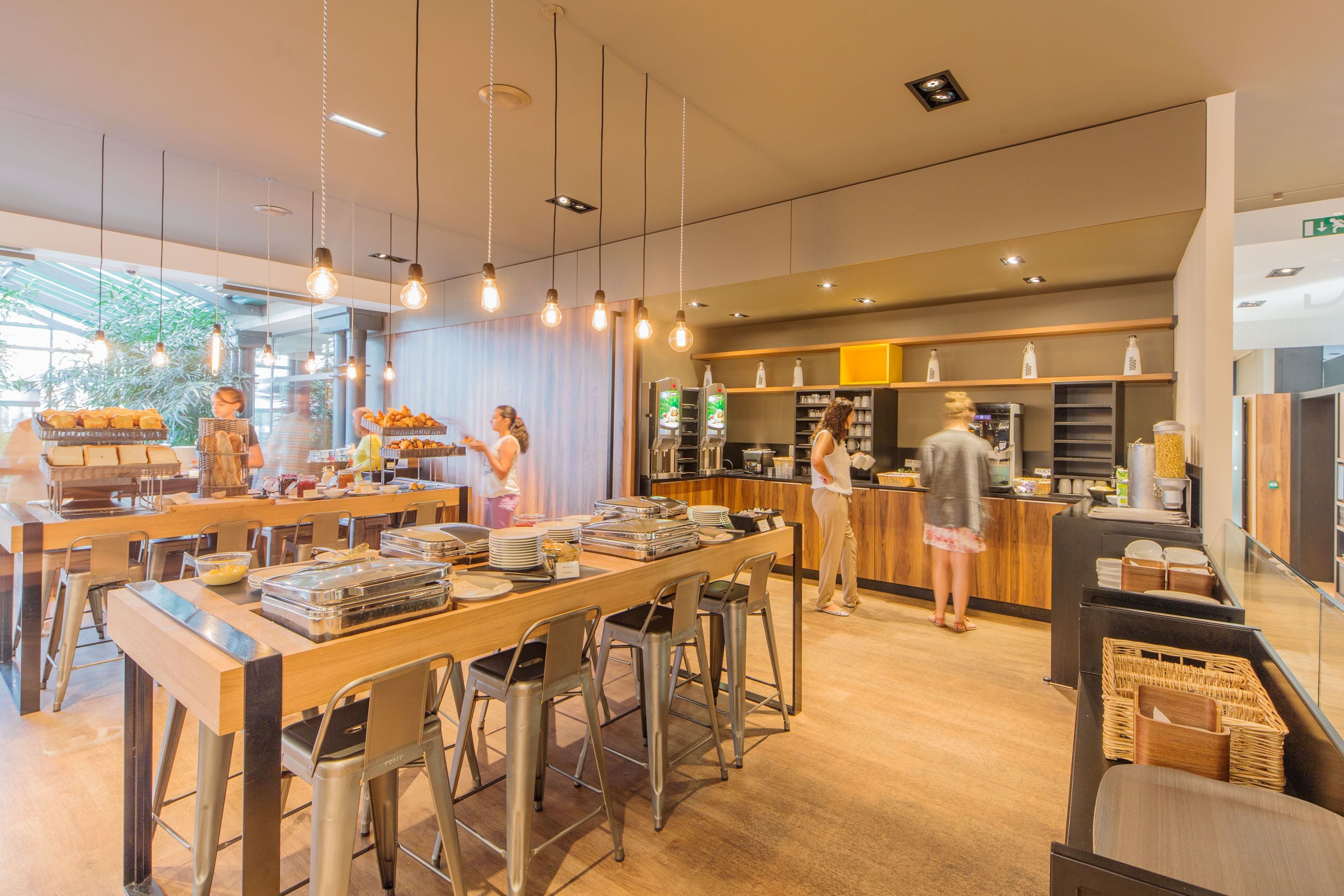 Un café moderno con taburetes, una zona de bufé y una barra con una máquina de café.