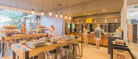 Un café moderno con taburetes, una zona de bufé y una barra con una máquina de café.