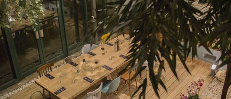 A dining area with a long wooden table, chairs, and hanging pendant lights.