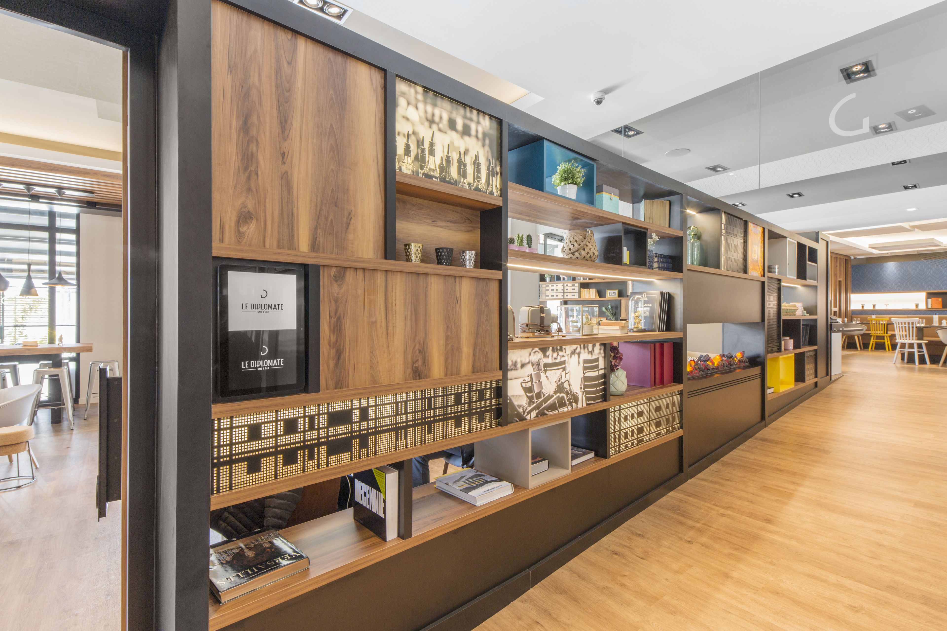 Una moderna biblioteca con scaffali in legno, libri e oggetti decorativi.