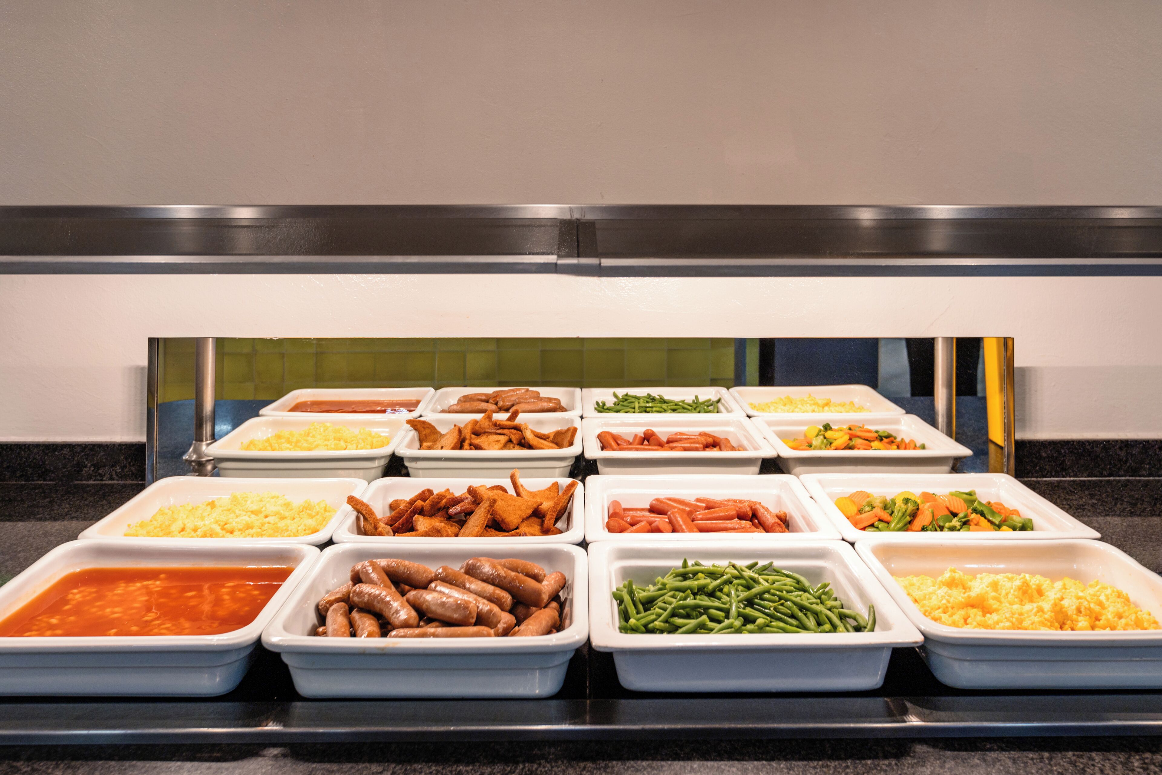 A buffet with various food options including meats, vegetables, and casseroles.
