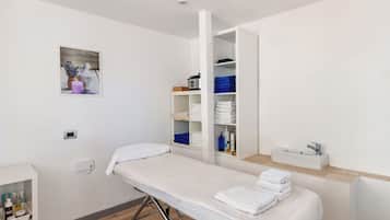 Guests can relax on a single examination bed with a white mattress and pillows.