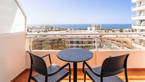 A balcony with a round table and two chairs, overlooking a coastal cityscape. - Catalonia Oro Negro (Arona)