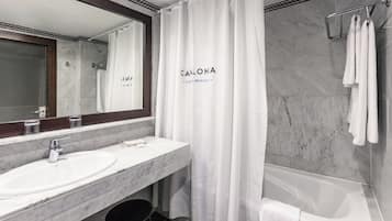 Un baño con lavamanos de mármol, bañera y cortina de ducha.