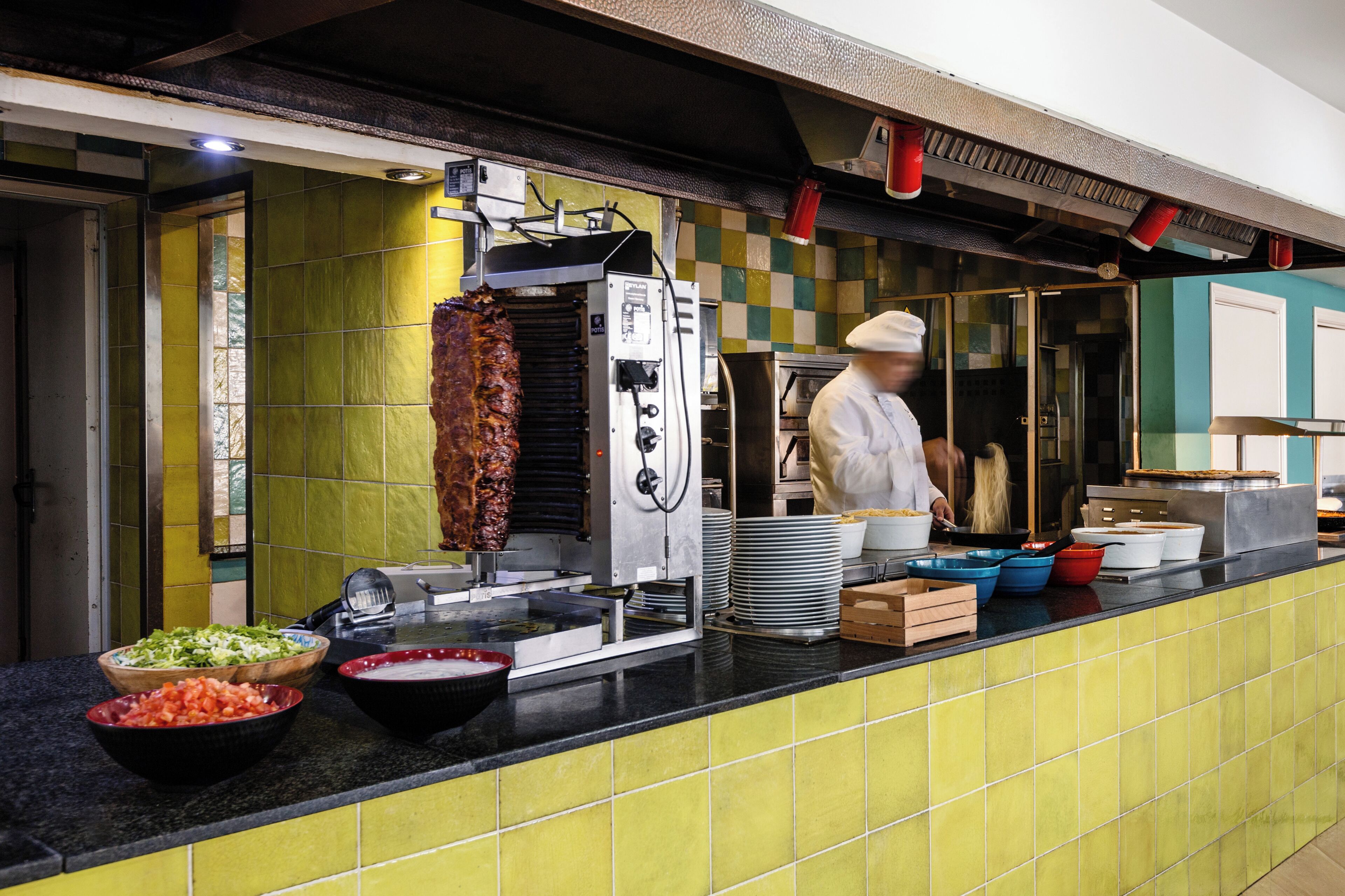 A kitchen area with a meat preparation station, including a rotisserie and various cooking utensils.