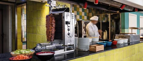 A kitchen area with a meat preparation station, including a rotisserie and various cooking utensils.