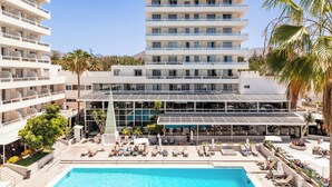 A hotel with multiple floors, a rooftop pool area with sun loungers, and a large building with a glass facade. - Catalonia Oro Negro (Arona)