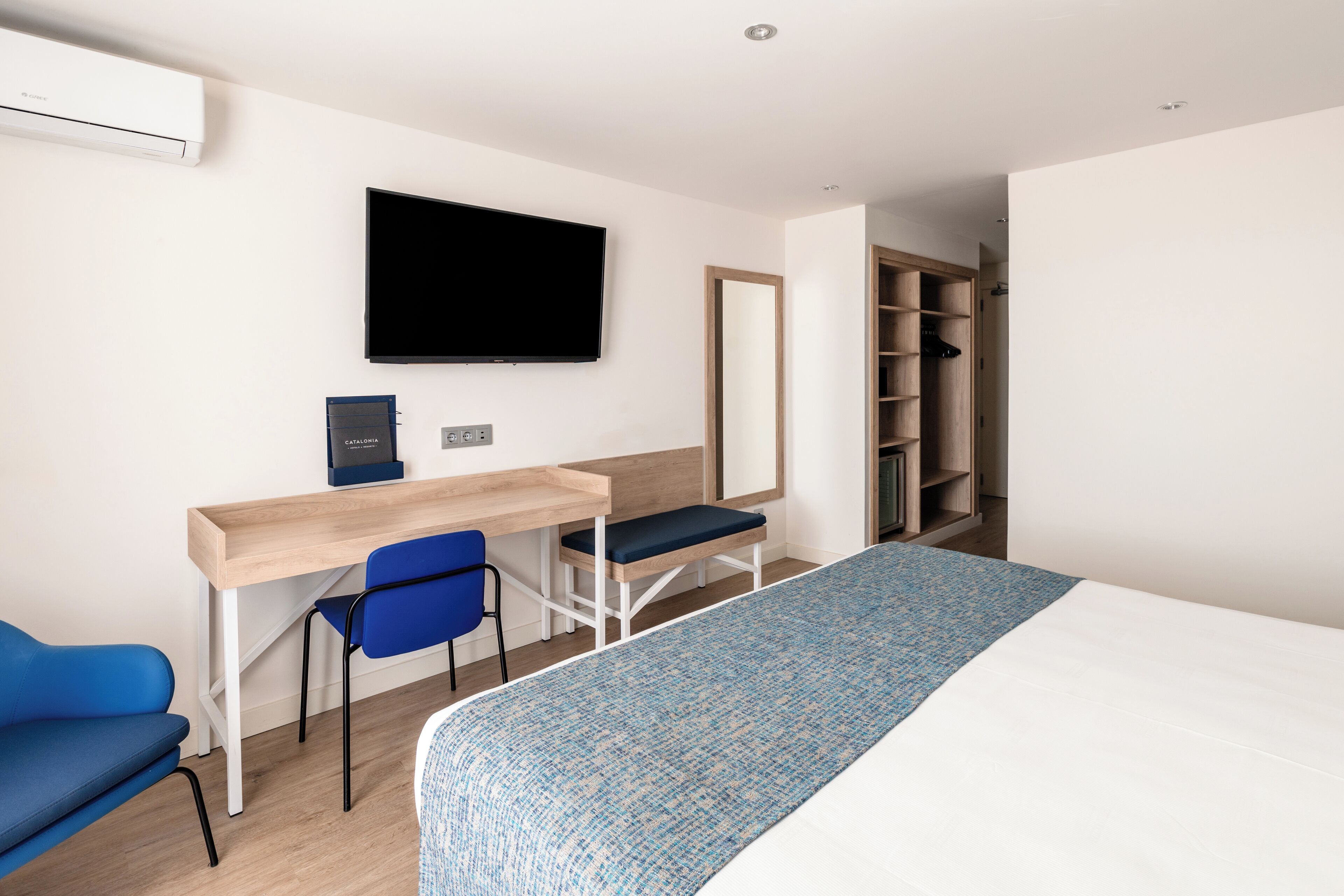 Une chambre d’hôtel comprenant un lit, un bureau avec une chaise, une télévision et une armoire.