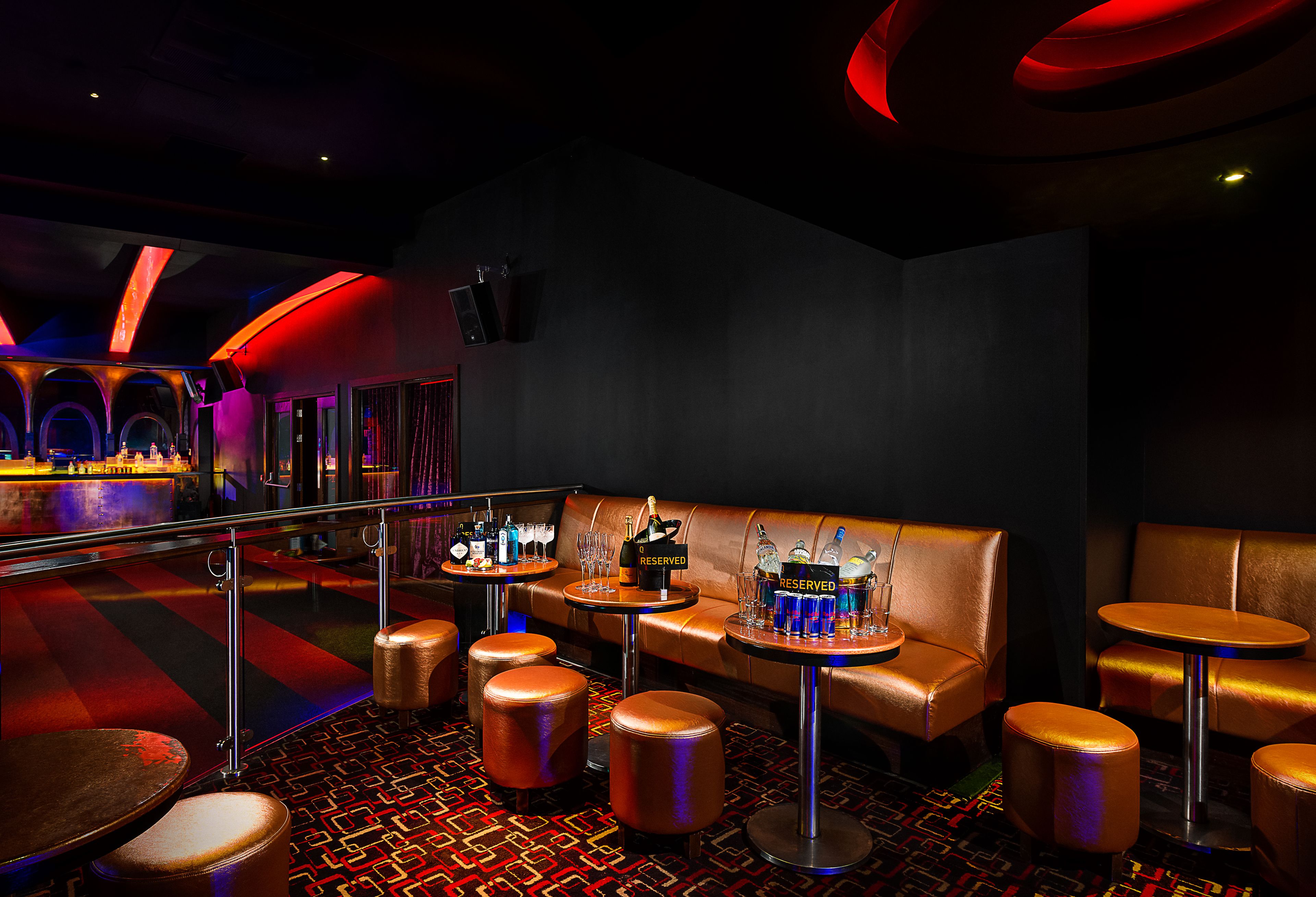 A bar area with leather seating, round tables, and stools.