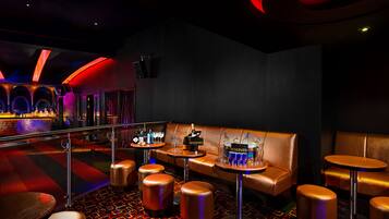 A bar area with leather seating, round tables, and stools.