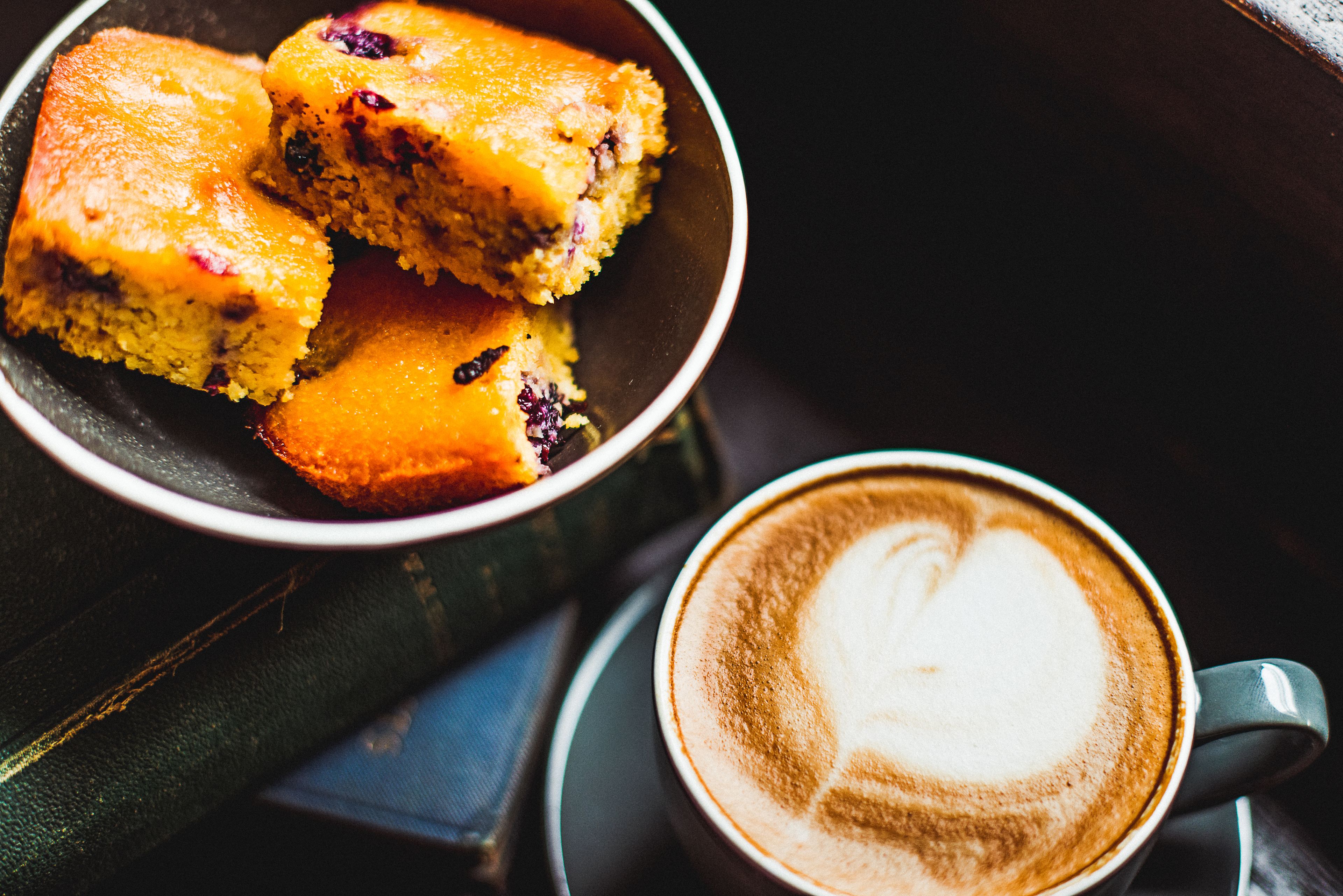 Un bol de pan de maíz y una taza de café con arte de latte.