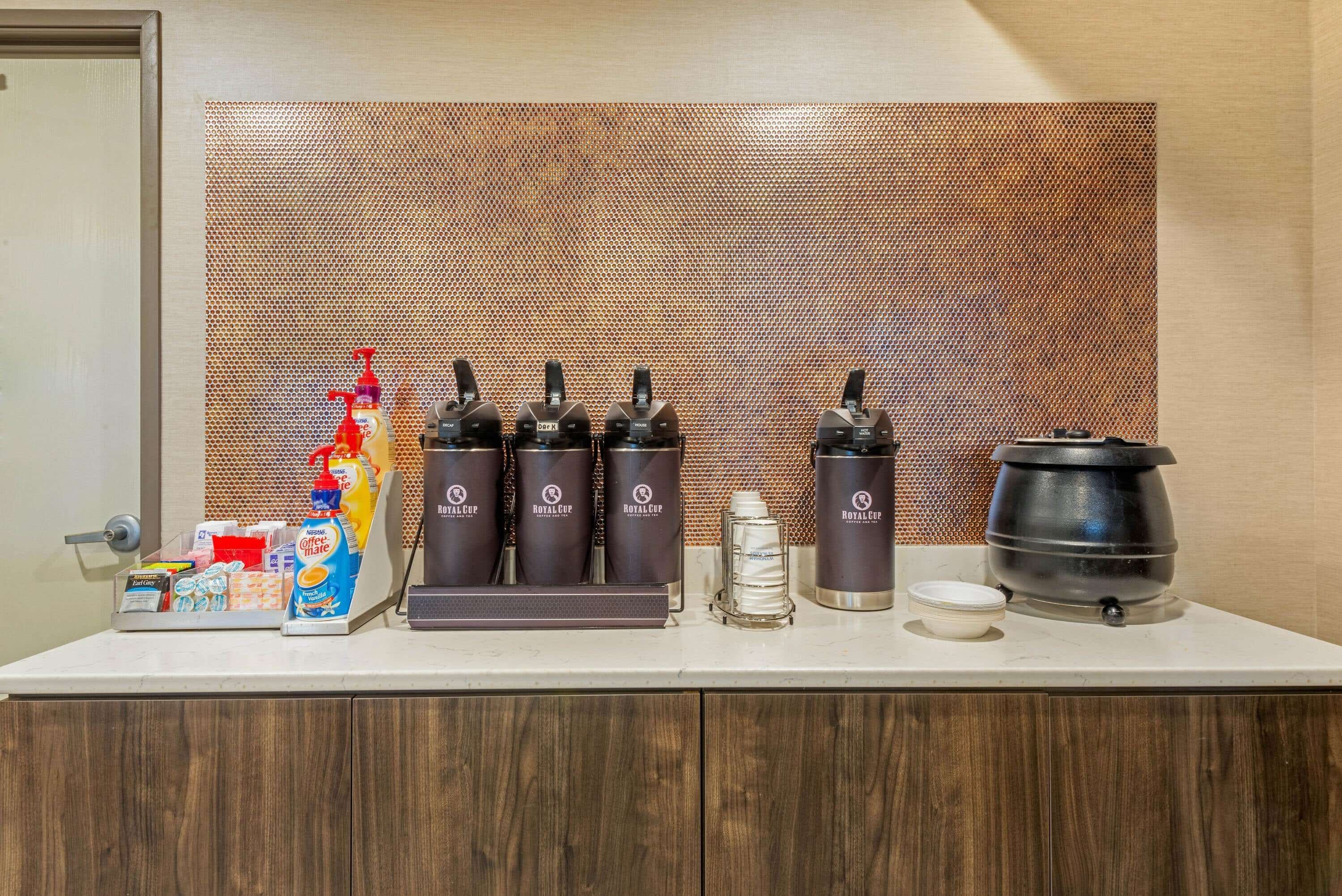 A coffee station with multiple Royal Cup branded dispensers, a coffee machine, and a selection of beverages and snacks.