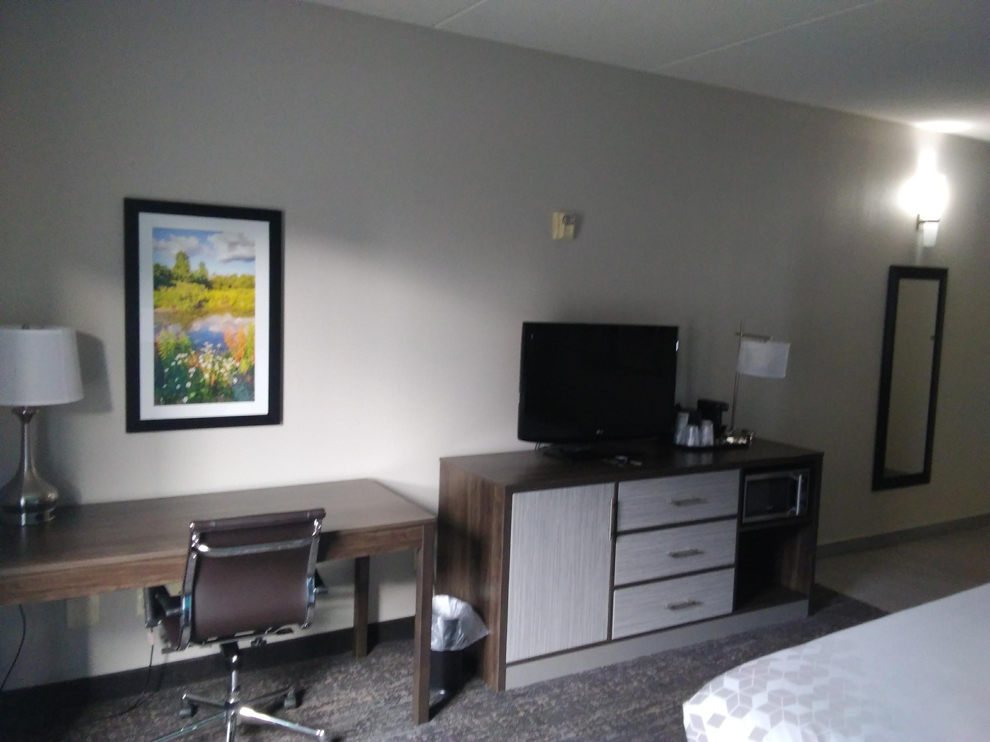 Een hotelkamer met een bureau, stoel, televisie en een bed.