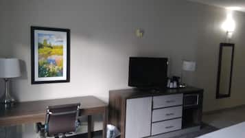 Een hotelkamer met een bureau, stoel, televisie en een bed.