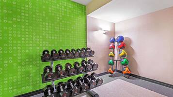 A gym with weight racks and dumbbells.