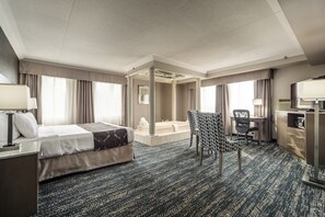 A hotel room with a bed, desk, chair, and a bathroom with a bathtub.