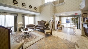 A spacious lobby with a high ceiling, patterned wallpaper, and a mix of seating including sofas and armchairs. - Monte Carlo Inn - Brampton Suites (Brampton)