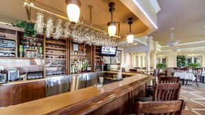 A bar area with a wooden counter, shelves with bottles and glasses, and hanging light fixtures. - Monte Carlo Inn - Brampton Suites (Brampton)