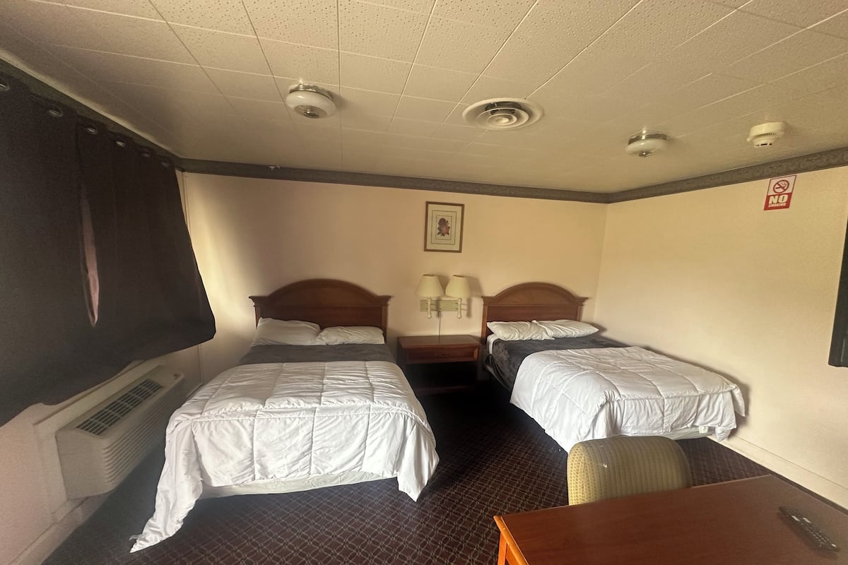 A hotel room with two beds, a desk, and a chair.