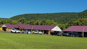 Ein Motel mit mehreren Gebäuden, einem Parkplatz und einer Bergkulisse.