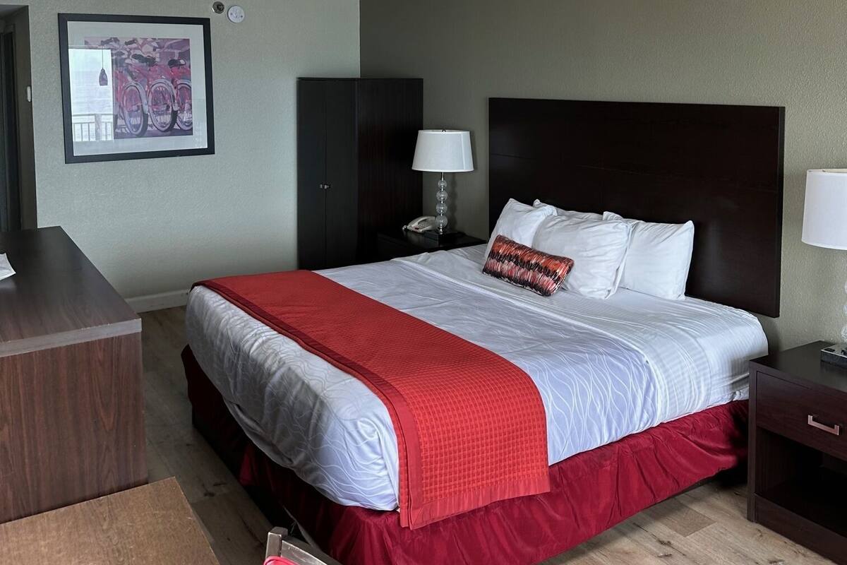 Habitación de hotel con una cama grande, un escritorio, una silla y un cuadro en la pared.