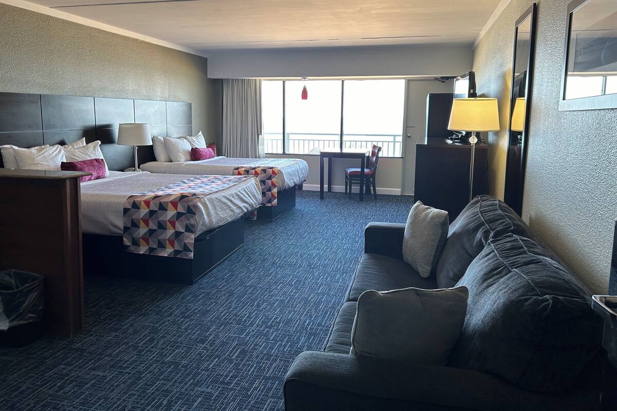 Habitación de hotel con dos camas, un sofá, un escritorio y una silla.
