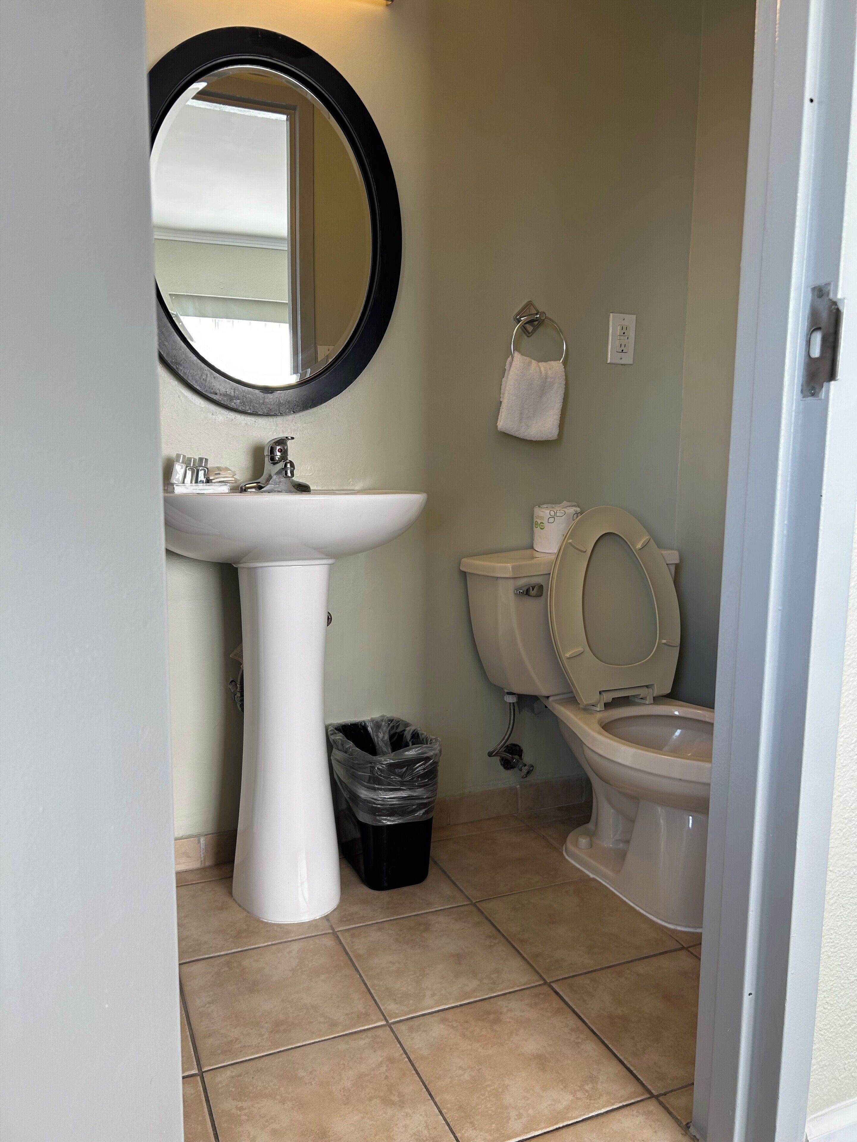 Une salle de bain avec un lavabo blanc, des toilettes et une poubelle.